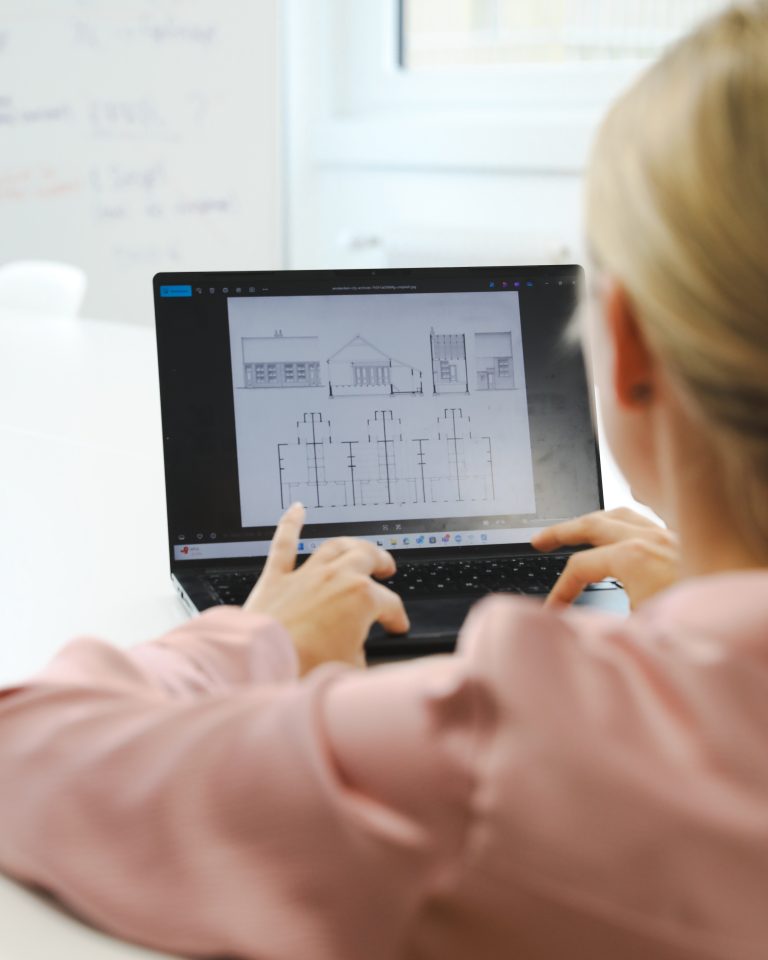 Frau arbeitet am PC, darauf ist ein Bauplan zu sehen, eIDAS